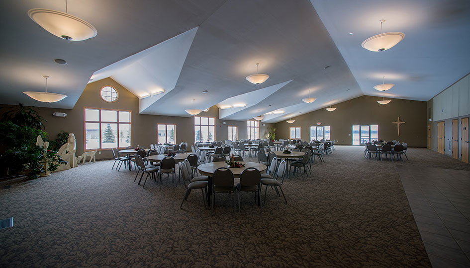 American Lutheran Church fellowship hall with round tables, chairs, and large windows