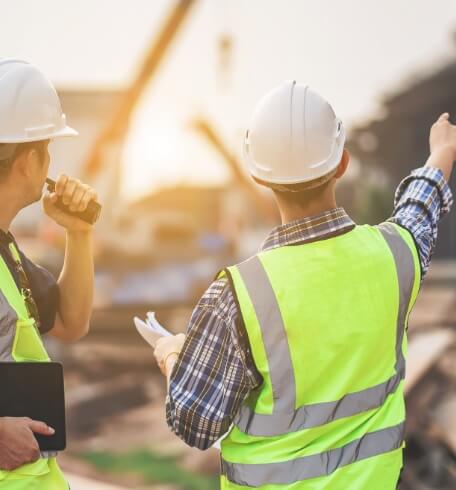 Construction managers in safety vests reviewing work at a jobsite