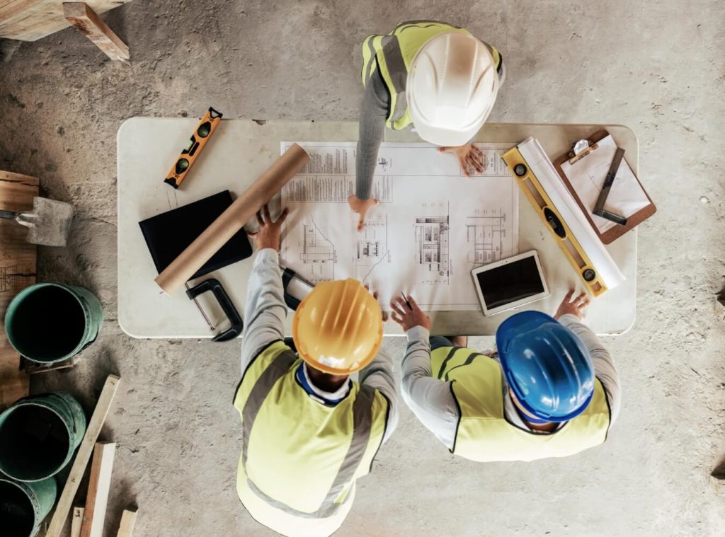 Construction team reviewing building plans at a jobsite table