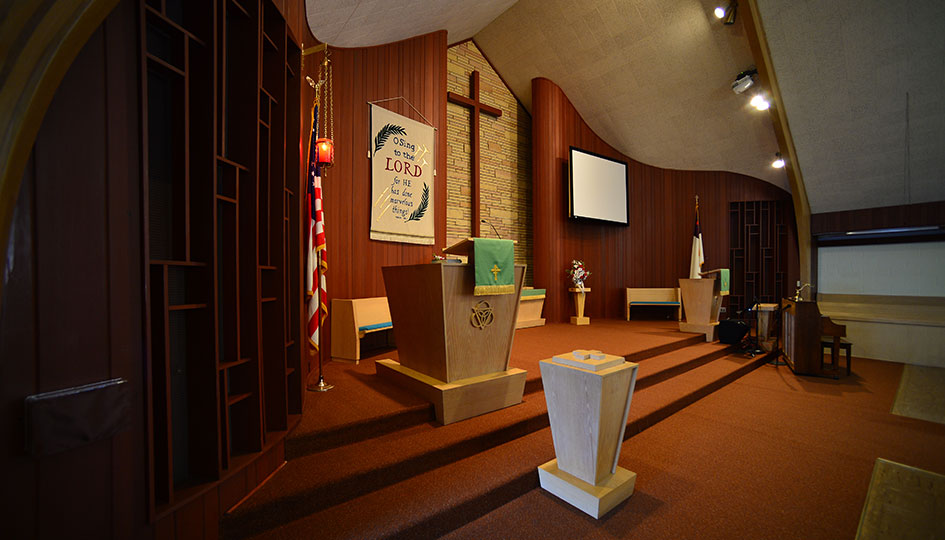 First Presbyterian Church chancel with pulpit, altar, cross, and wood paneling