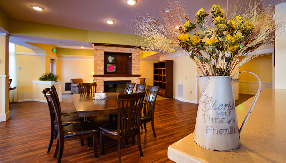 Ortonville independent living community room with dining table, fireplace, and floral decor