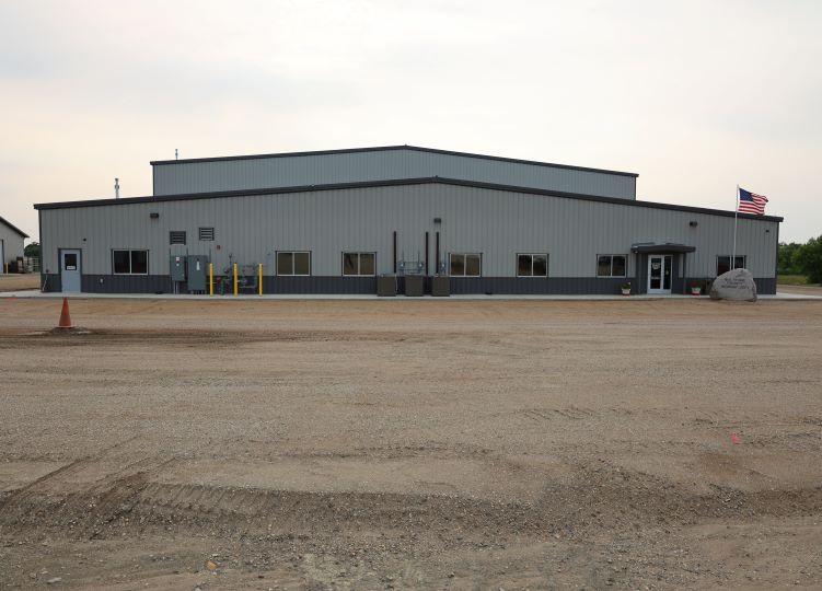 Public works maintenance facility front exterior with gravel lot and flag