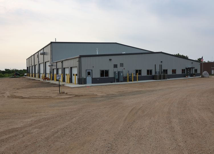 Public works maintenance facility side exterior with service bays and gravel drive