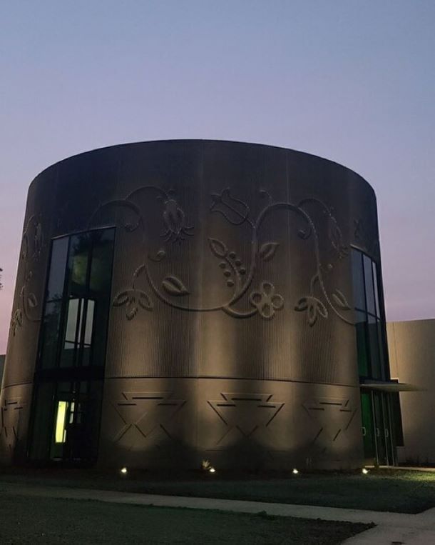 Round building exterior with decorative wall details illuminated at night