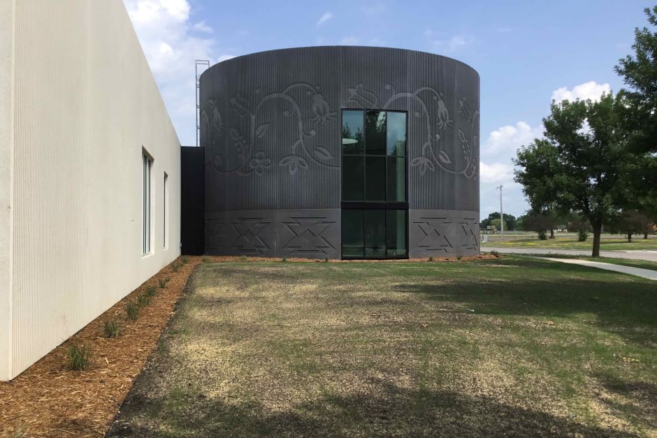 Side exterior of round building with decorative wall details and tall windows